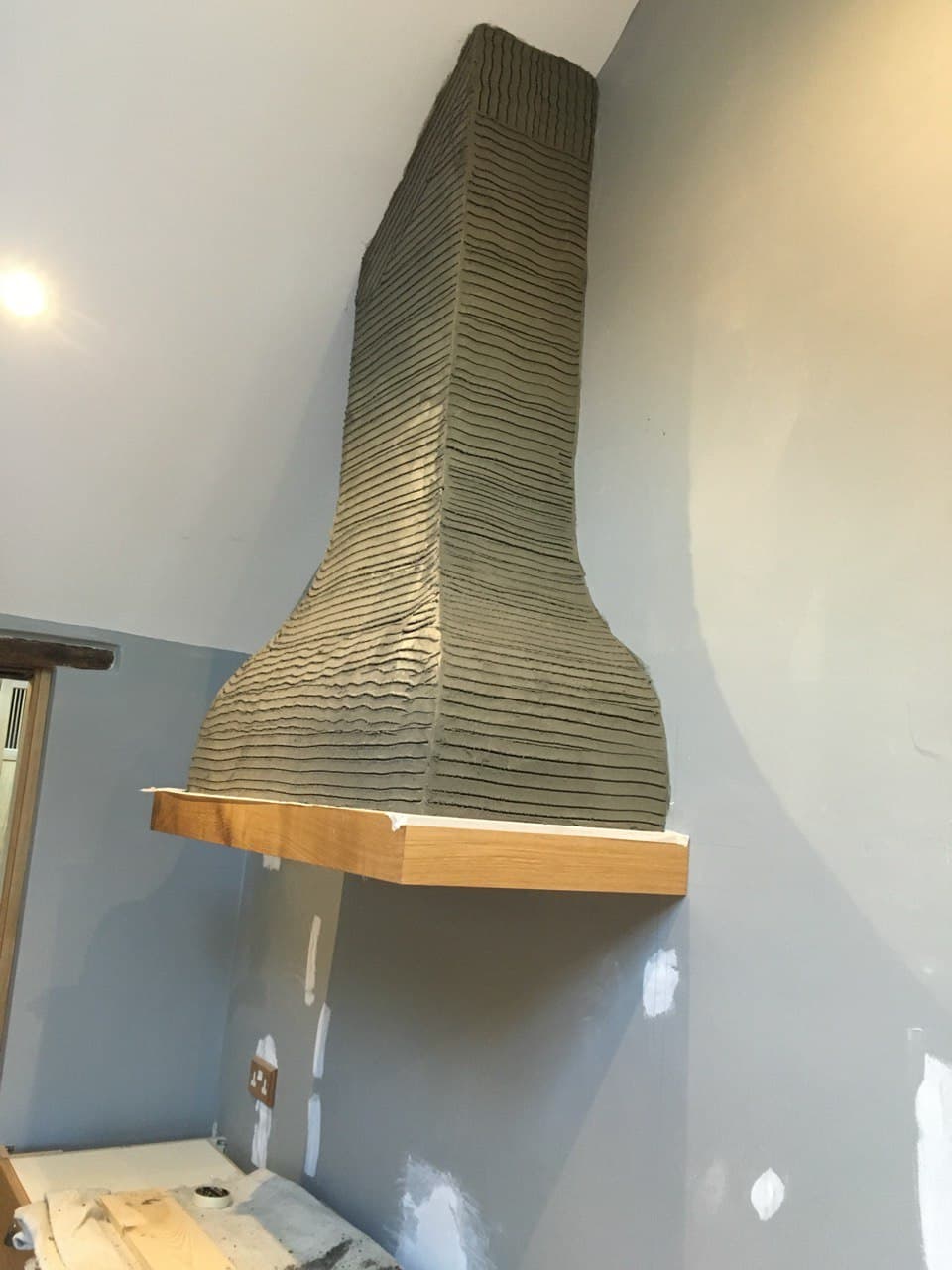Custom bespoke chimney hood with textured render finish and oak mantel shelf by Spiby Build