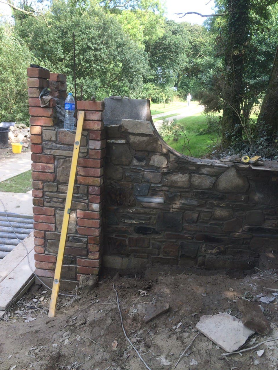 Curved stone boundary wall with brick pillar during construction at a North Cornwall property entrance