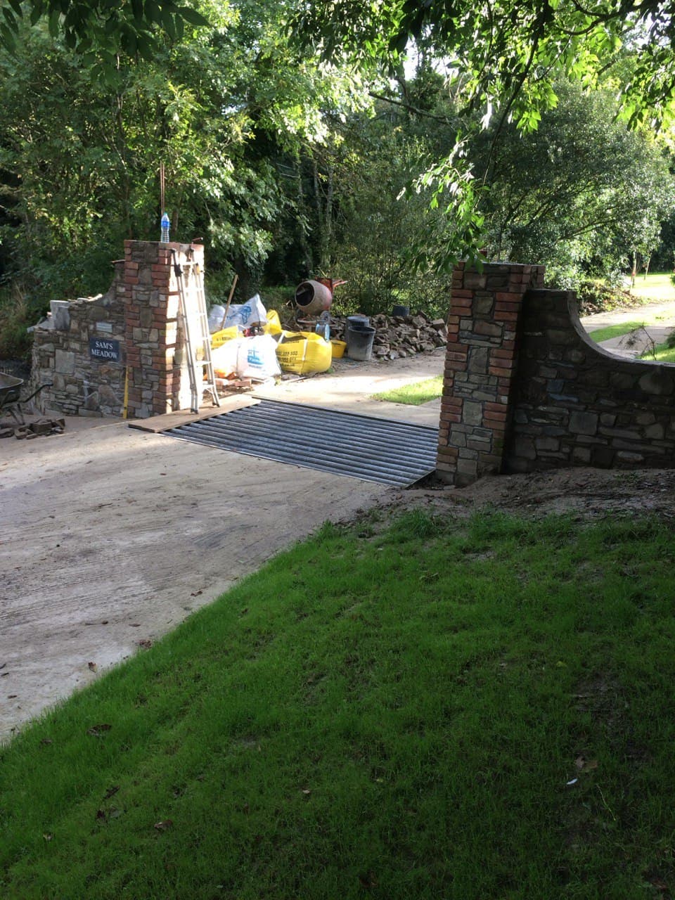Reclaimed stone and brick entrance pillars with curved boundary wall built by Spiby Build in North Cornwall