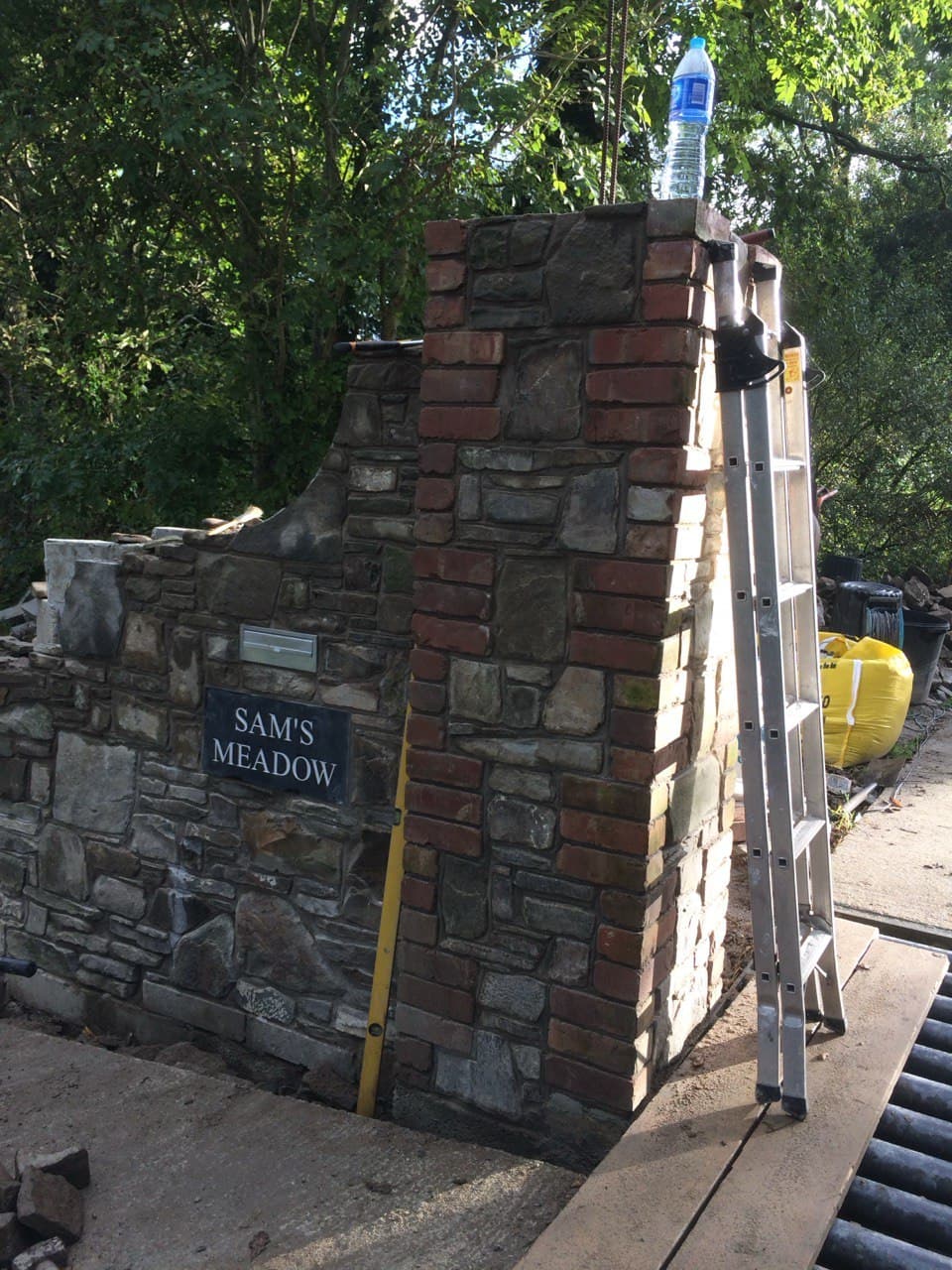 Entrance pillar under construction showing reclaimed stone and brick with Sam's Meadow name sign