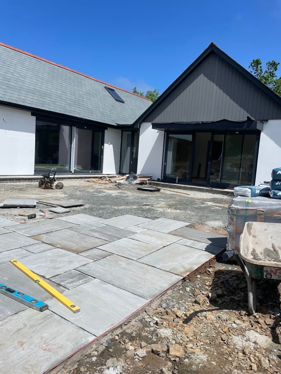 Front elevation of new build property with white silicone render slate roof and early stage patio construction at Thornbury Devon