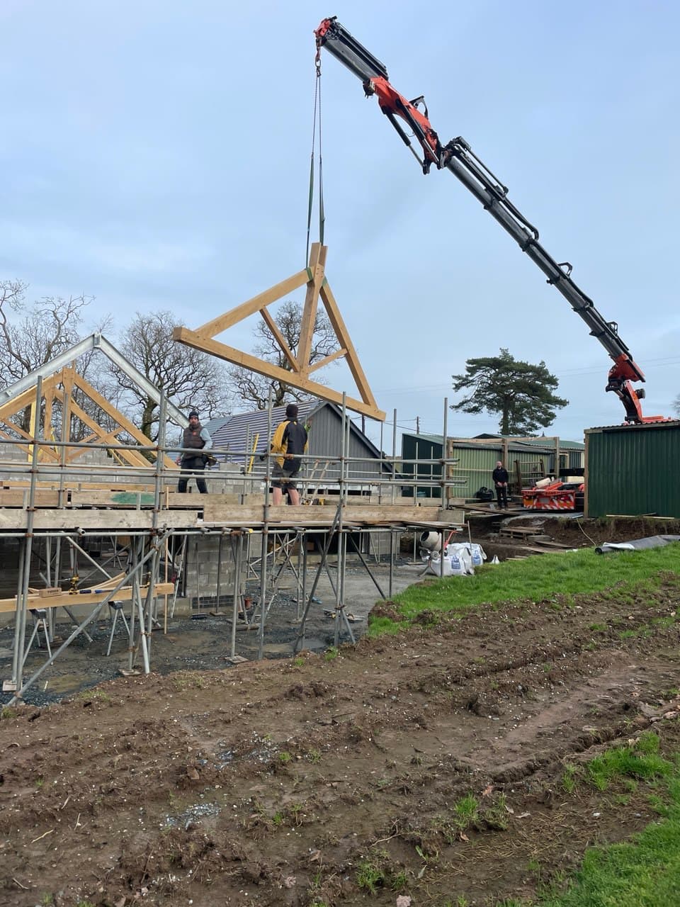 Spiby Build new build construction project showing crane lifting timber roof trusses in Devon