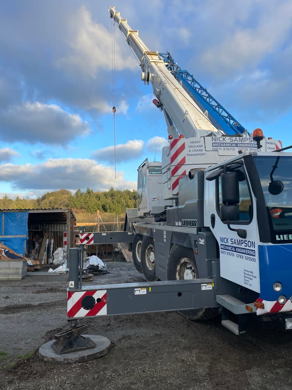 Rear view of Liebherr mobile crane with stabilisers deployed during oak truss installation at Thornbury Devon new build